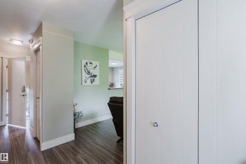 Entryway featuring wood-finish flooring, white baseboards, and a white bi-fold closet door with a silver knob - 14814 104 Avenue Nw, Edmonton, AB - Indoor Photo Showing Other Room