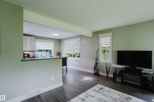 Open-concept living area featuring wood-finish flooring, light green wall paint, and white trim - 14814 104 Avenue Nw, Edmonton, AB - Indoor Photo Showing Living Room