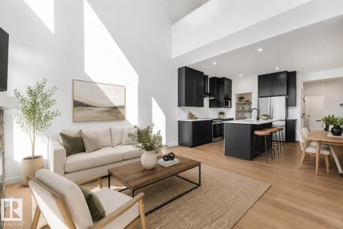 Vaulted ceiling with bright walls, wood-finish flooring, a contemporary kitchen with dark cabinetry, stainless steel appliances, and a central island - 511 157 Avenue Ne, Edmonton, AB 