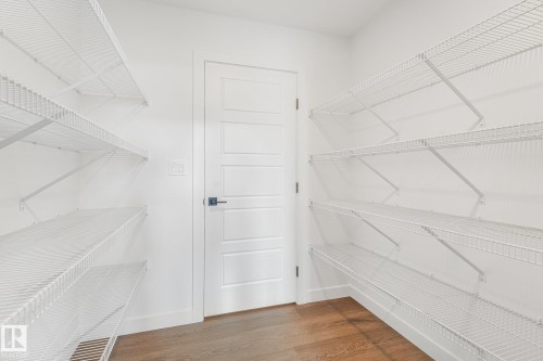 White wire shelving system, contemporary paneled door, dark hardware, wood-finish flooring, and crisp white walls - 511 157 Avenue Ne, Edmonton, AB 