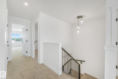 Recessed lighting and a decorative pendant light fixture illuminate the hallway and staircase - 511 157 Avenue Ne, Edmonton, AB 