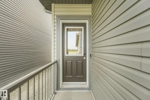 Gray vinyl siding exterior with a dark-paneled entry door featuring a decorative glass insert - 511 157 Avenue Ne, Edmonton, AB 
