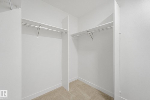 Spacious walk-in closet featuring dual clothing rods, generous shelving, and wood-finish flooring throughout - 511 157 Avenue Ne, Edmonton, AB 