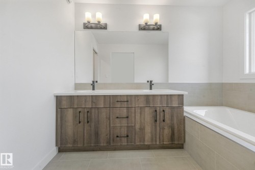 Double vanity with wood-finish cabinetry, white countertop, and dark-toned fixtures - 511 157 Avenue Ne, Edmonton, AB 