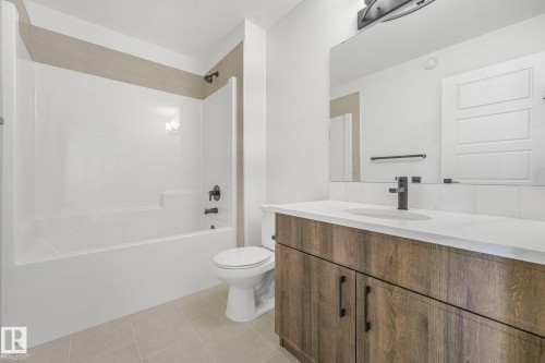Contemporary bathroom featuring a wood-finish vanity with a white countertop, rectangular sink, and matte black faucet - 511 157 Avenue Ne, Edmonton, AB 