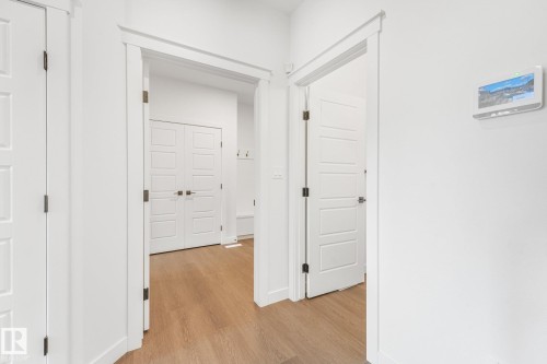 Light wood-finish flooring with white trim and solid core doors - 511 157 Avenue Ne, Edmonton, AB 