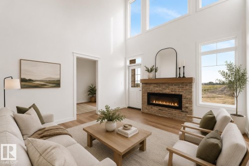 Two-story living area with wood-finish flooring, a brick-surround fireplace with a wood mantle, and an abundance of natural light through multiple windows - 511 157 Avenue Ne, Edmonton, AB 