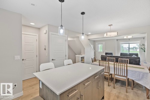 Open-concept living space featuring wood-finish flooring, recessed lighting, and a kitchen island with a light-toned countertop - #22 3025 151 Av Nw, Edmonton, AB - Indoor