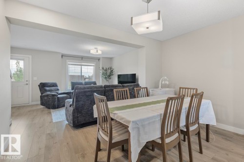 Open-concept dining and living areas featuring light wood-finish flooring, neutral paint palette, and recessed lighting - #22 3025 151 Av Nw, Edmonton, AB - Indoor Photo Showing Dining Room