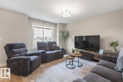 Living area with light wood-finish flooring and a central window - #22 3025 151 Av Nw, Edmonton, AB - Indoor Photo Showing Living Room