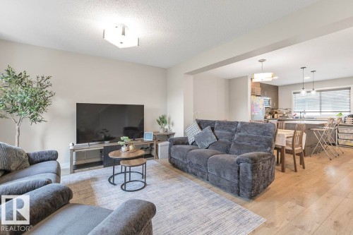Spacious living area featuring light wood-finish flooring and neutral wall tones - #22 3025 151 Av Nw, Edmonton, AB - Indoor Photo Showing Living Room