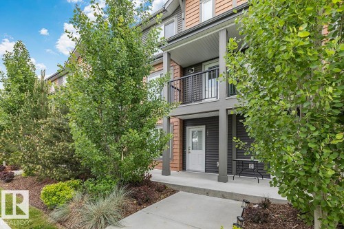 Multi-level building exterior featuring a wood-siding facade and a ground-level patio - #22 3025 151 Av Nw, Edmonton, AB - Outdoor
