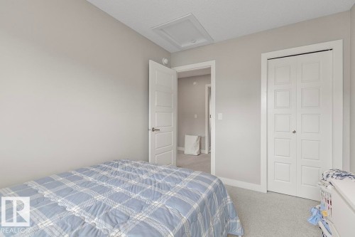 Bright room featuring light grey wall paint, plush carpeting, a white paneled door, and a matching bifold closet door - #22 3025 151 Av Nw, Edmonton, AB - Indoor Photo Showing Bedroom