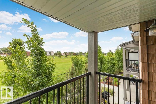 Private balcony with black metal railings, offering open green space vistas and mature tree landscaping - #22 3025 151 Av Nw, Edmonton, AB - Outdoor With Exterior