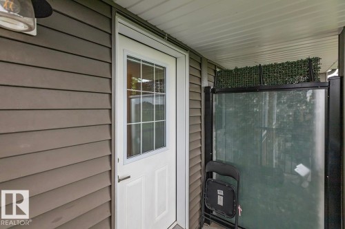 White paneled exterior door with grid-patterned glass, complemented by horizontal siding - #22 3025 151 Av Nw, Edmonton, AB - Outdoor With Exterior