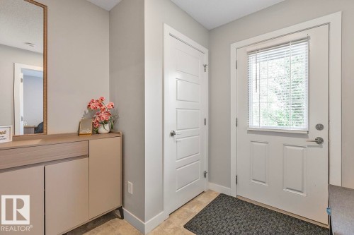 Front entry featuring a white paneled door with an integrated window, light-toned walls, and wood-finish flooring - #22 3025 151 Av Nw, Edmonton, AB - Indoor Photo Showing Other Room