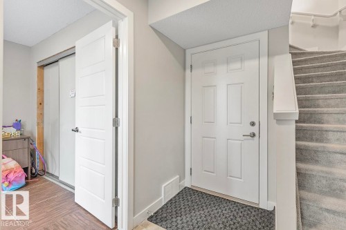 Entryway featuring a white paneled door, gray wall paint, and a carpeted staircase with white trim - #22 3025 151 Av Nw, Edmonton, AB - Indoor Photo Showing Other Room