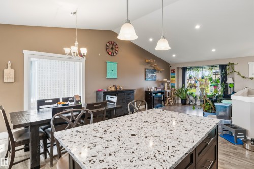 Kitchen island with a speckled countertop, dark wood-finish cabinetry, and pendant lighting - 4927 57 Avenue, Cold Lake, AB 