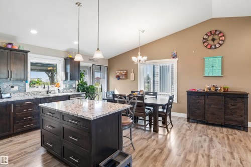 Spacious kitchen featuring dark wood cabinetry, a central island with a light-toned countertop, and wood-finish flooring - 4927 57 Avenue, Cold Lake, AB 