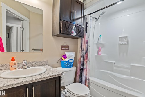 Integrated shower and tub combination, dark wood-finish vanity with a light speckled countertop, undermount sink, and a wall-mounted mirror - 4927 57 Avenue, Cold Lake, AB 