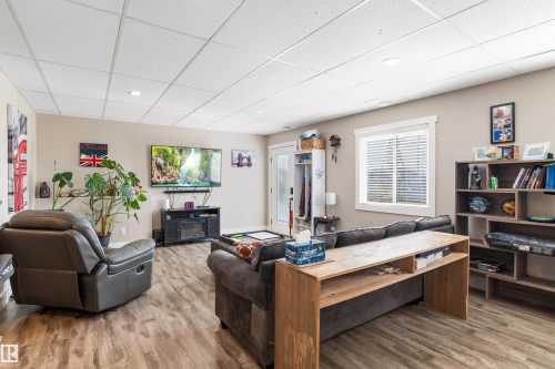 Spacious living area featuring wood-finish flooring, recessed lighting, and a window with blinds - 4927 57 Avenue, Cold Lake, AB 