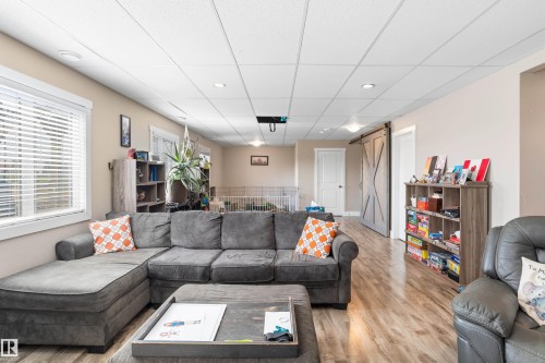 Recessed lighting illuminates the open living area featuring wood-finish flooring, a white window frame, and a barn-style door - 4927 57 Avenue, Cold Lake, AB 