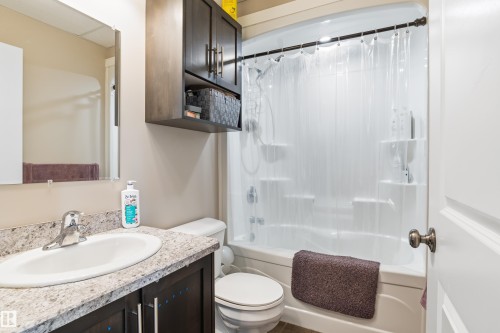 Bathroom featuring a vanity with an undermount sink, a two-piece toilet, a shower/tub combination, and wall-mounted storage cabinetry - 4927 57 Avenue, Cold Lake, AB 