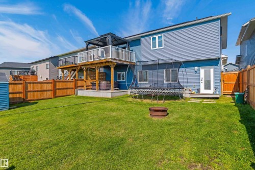 Fenced backyard featuring a manicured lawn, a raised wooden deck with a gazebo, and a lower-level concrete patio - 4927 57 Avenue, Cold Lake, AB 