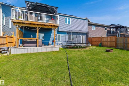 Expansive grassy yard with a two-story deck featuring a pergola-covered upper level and a ground-level hot tub - 4927 57 Avenue, Cold Lake, AB 