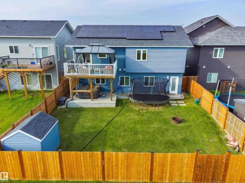 Rear exterior with blue siding, elevated deck with white railings, ground-level patio, and a storage shed - 4927 57 Avenue, Cold Lake, AB 