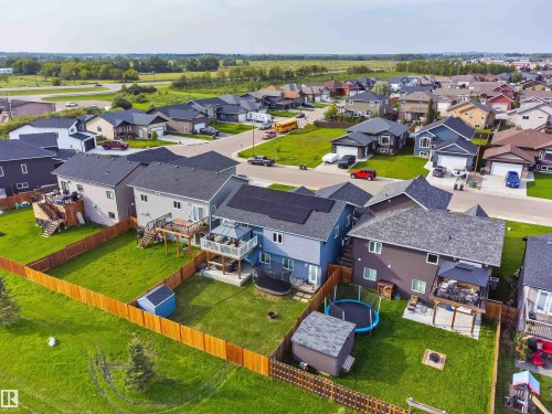 Fenced backyard with expansive lawn, multiple tiered decks, and a covered patio structure - 4927 57 Avenue, Cold Lake, AB 