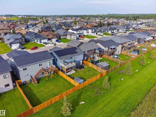 Fenced property with a manicured lawn, an elevated deck, and mature trees - 4927 57 Avenue, Cold Lake, AB 