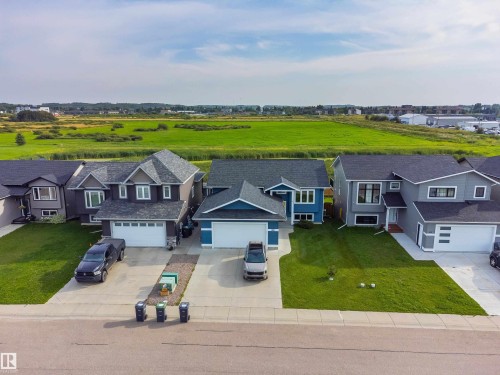 Blue exterior with dark gray roofing, a white garage door, and a concrete driveway - 4927 57 Avenue, Cold Lake, AB 