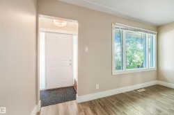Wood-finish flooring throughout, white trim, and a three-pane window - 