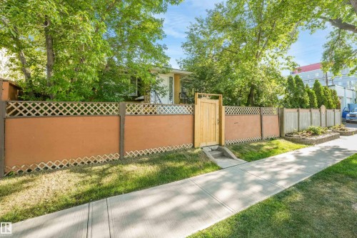 Privacy fence with lattice top, natural wood gate, and a concrete pathway - 9347 105 Avenue Nw, Edmonton, AB 
