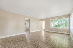 Spacious interior featuring wood-look tile flooring, neutral wall tones, and a large picture window - 