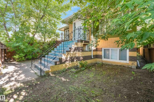 Exterior features brick siding, a concrete staircase with wrought iron railings, and a lower-level window with horizontal blinds - 9347 105 Avenue Nw, Edmonton, AB 