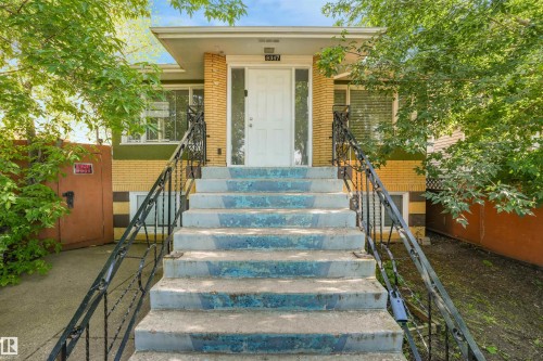 Concrete exterior staircase with wrought iron railings leading to a white entry door - 9347 105 Avenue Nw, Edmonton, AB 