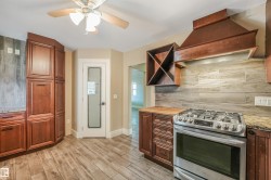 Stainless steel range with a built-in hood, wood-finish cabinetry, wood-finish flooring, wood-finish backsplash, and a ceiling fan - 