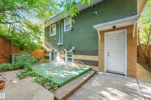 Concrete patio with a white paneled door, awning, and a privacy fence - 9347 105 Avenue Nw, Edmonton, AB 