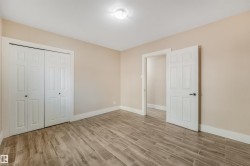 Wood-finish flooring with a neutral wall color, white trim, and a ceiling-mounted light fixture - 