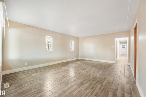 Spacious interior with neutral wall paint, multiple windows, and extensive wood-finish flooring - 9347 105 Avenue Nw, Edmonton, AB 