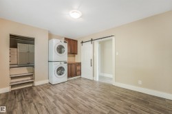 Laundry area with wood-finish flooring, built-in cabinetry, and a sliding barn door - 
