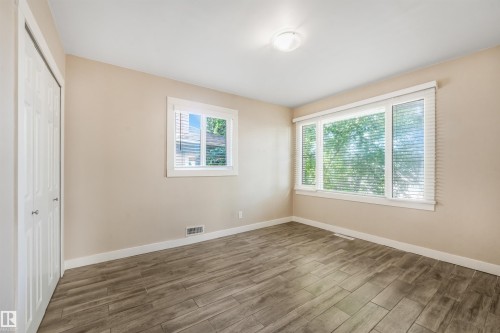 Room featuring wood-finish flooring, neutral wall paint, and multiple windows - 9347 105 Avenue Nw, Edmonton, AB 