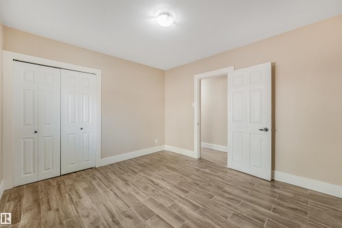 Wood-finish flooring with a neutral wall color, white trim, and a ceiling-mounted light fixture - 9347 105 Avenue Nw, Edmonton, AB 