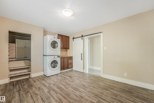 Laundry area with wood-finish flooring, built-in cabinetry, and a sliding barn door - 9347 105 Avenue Nw, Edmonton, AB 