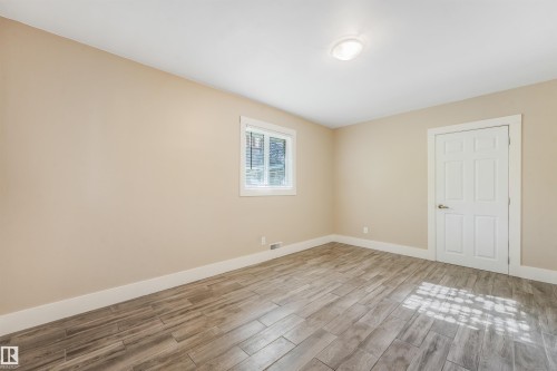 Wood-finish flooring, single window with white trim, flush mount ceiling light, and a paneled door with brushed nickel hardware - 9347 105 Avenue Nw, Edmonton, AB 
