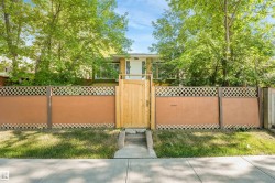 Front exterior featuring a privacy fence with lattice accents, a solid wood gate, and mature trees providing natural screening - 