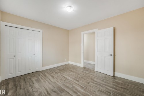 Light-toned wall paint, wood-finish plank flooring, white trim, recessed lighting, and white paneled doors - 9347 105 Avenue Nw, Edmonton, AB 