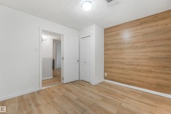 Wood-finish accent wall, wood-finish flooring, recessed lighting, white interior doors, and a built-in closet - 